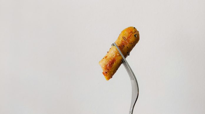 A fork holding up a piece of food on a blank background.